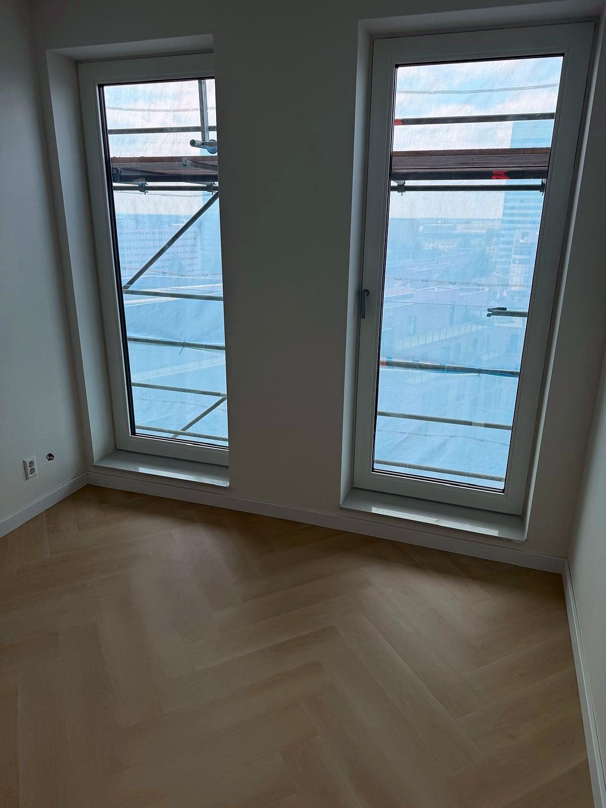 Hoekkamer met twee kozijnen en een doorlopende visgraatvloer, klaar voor oplevering