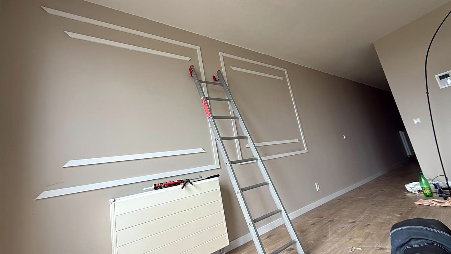 Slaapkamerwand waarop decoratief lijstwerk wordt aangebracht; de latten zijn uitgelijnd en de eerste vlakken zitten op hun plek